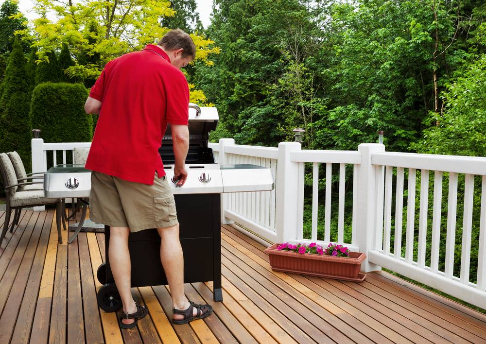 man and grill on a deck