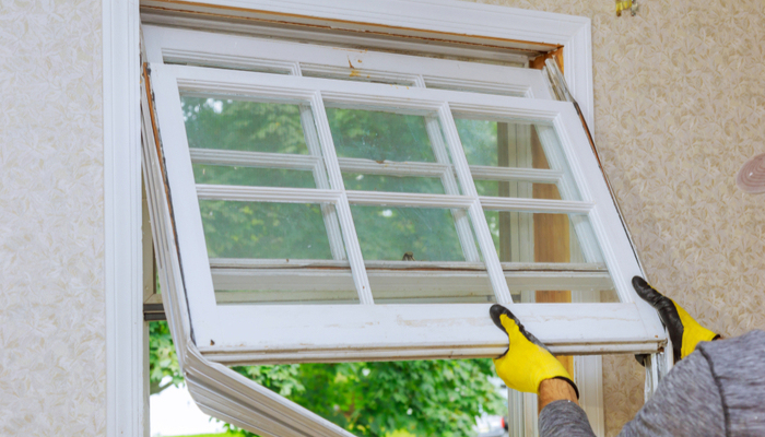 Man with yellow gloves removes white window of a house