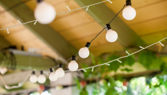 Beautiful outdoor string lights hanging on a line in backyard outside screened in porch