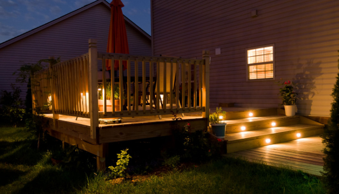 Wooden deck and patio of family home at night with floor lights
