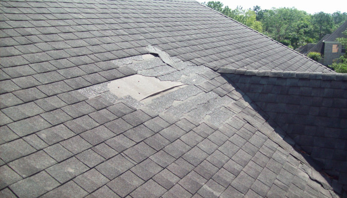 Damaged roof with missing shingles caused by storm