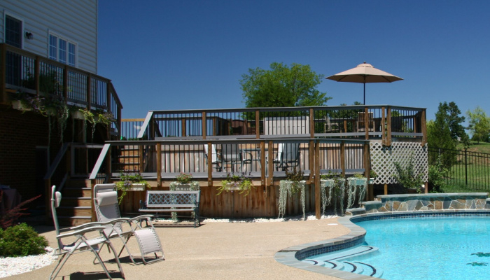 Backyard Pool in summer with surrounding beautiful multi-level deck photo taken in the morning