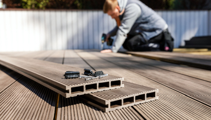 Worker in a gray hoodie installing wood plastic composite decking boards