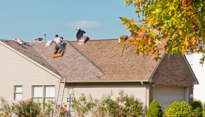 Roofers repairing the roof of a house in the suburbs in the fall