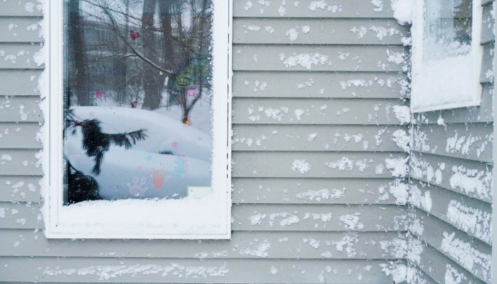 House with wooden siding covered in snow after a blizzard