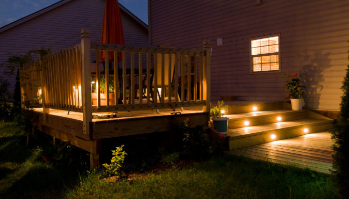 Simple wooden deck and patio with lighting of family home at night