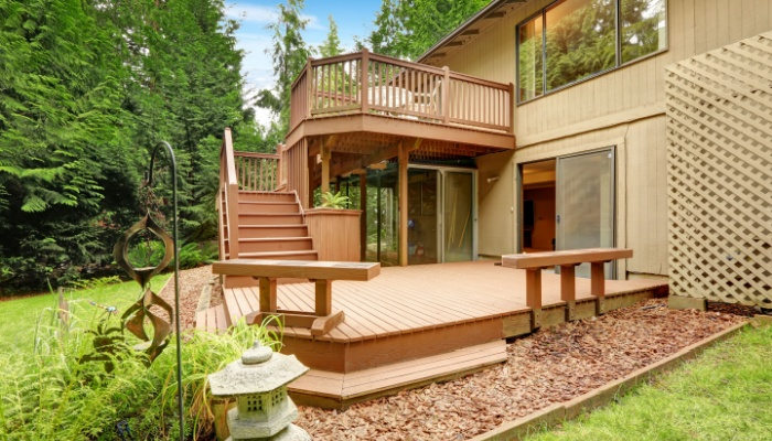 Backyard view of a house with walkout wooden deck and patio
