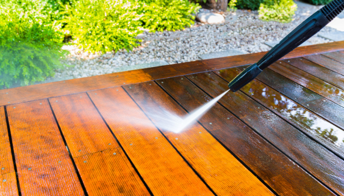 Cleaning the wooden deck with a pressure washer after winter months - sharpness on the terrace board under a stream of water